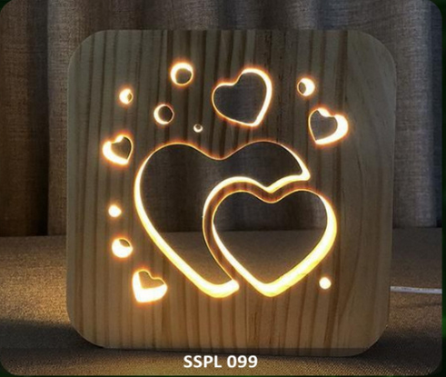Wooden night light with heart designs and warm glow on a textured surface.