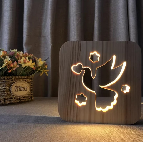 Wooden night light with bird design on a surface with a curtain background