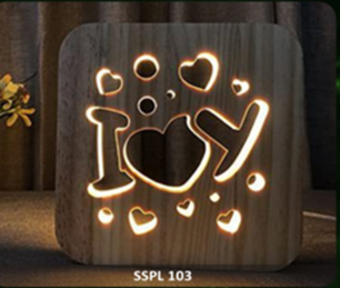 Wooden night light with cut-out design of a heart and hands holding a heart, glowing softly.